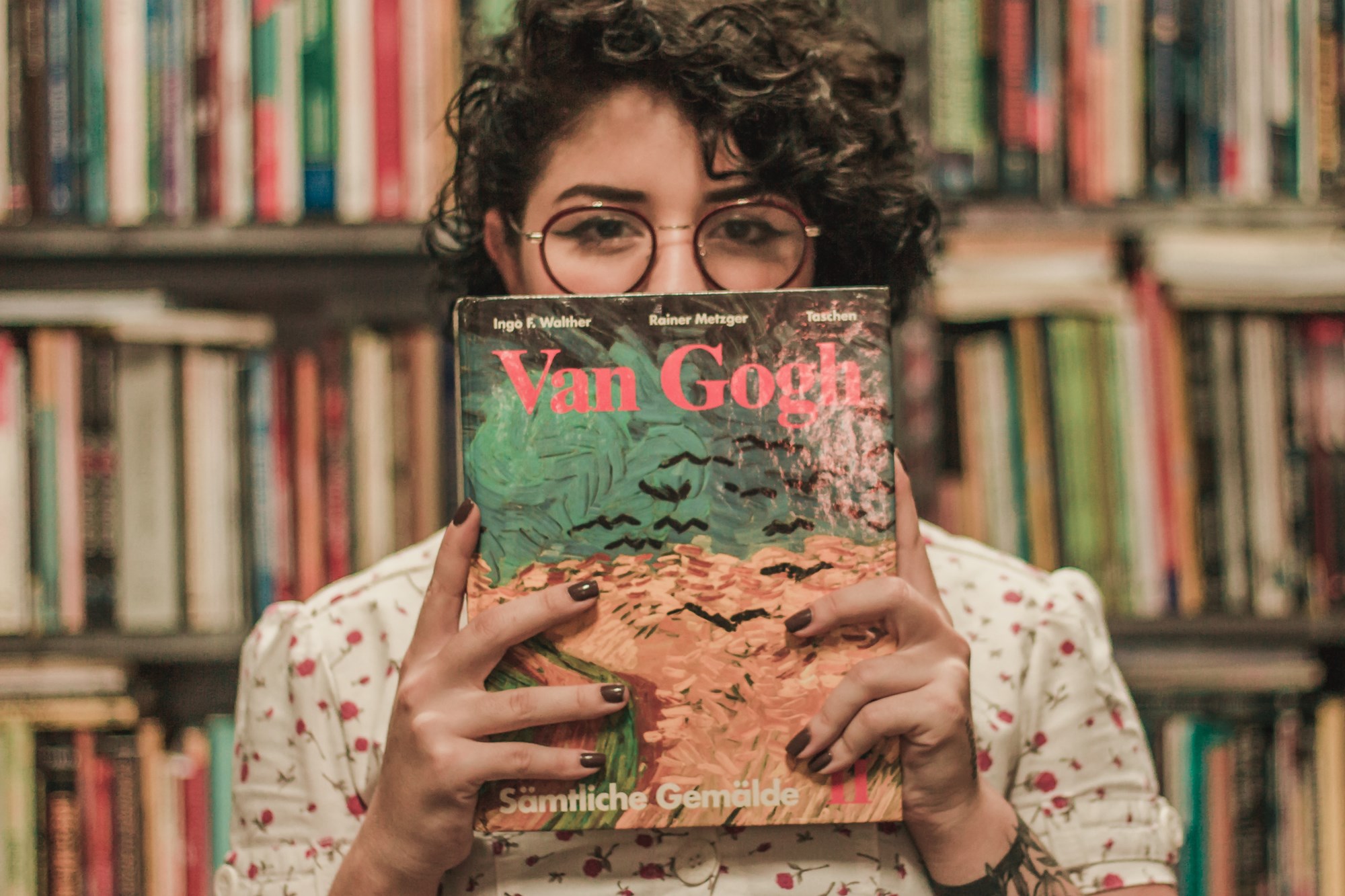 Woman holding a Van Gogh book in front of a book shelf 