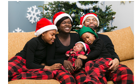 Image of mother, father with three children hugging, smiling on sofa, wearing Santa hats.