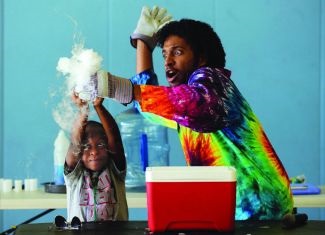 an adult and child wearing tie dye performing a science experiment