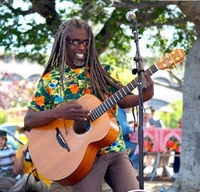 photo of musician Asheba playing a guitar outside