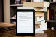 e-reader device next to a stack of books