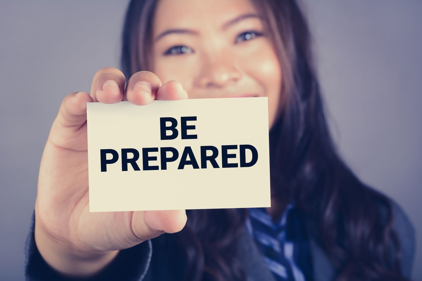 Young woman holding up a card that says "be prepared"