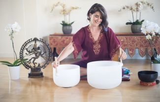 woman sitting on floor surrounded by large bowls and flowers