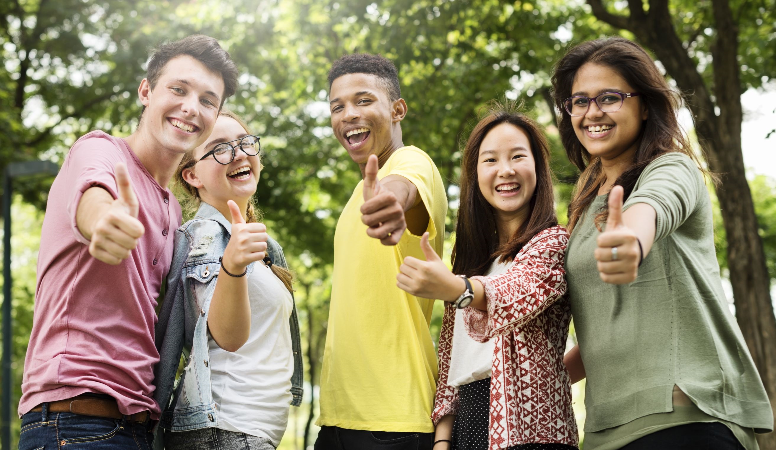 Five smiling teens with their thumbs up