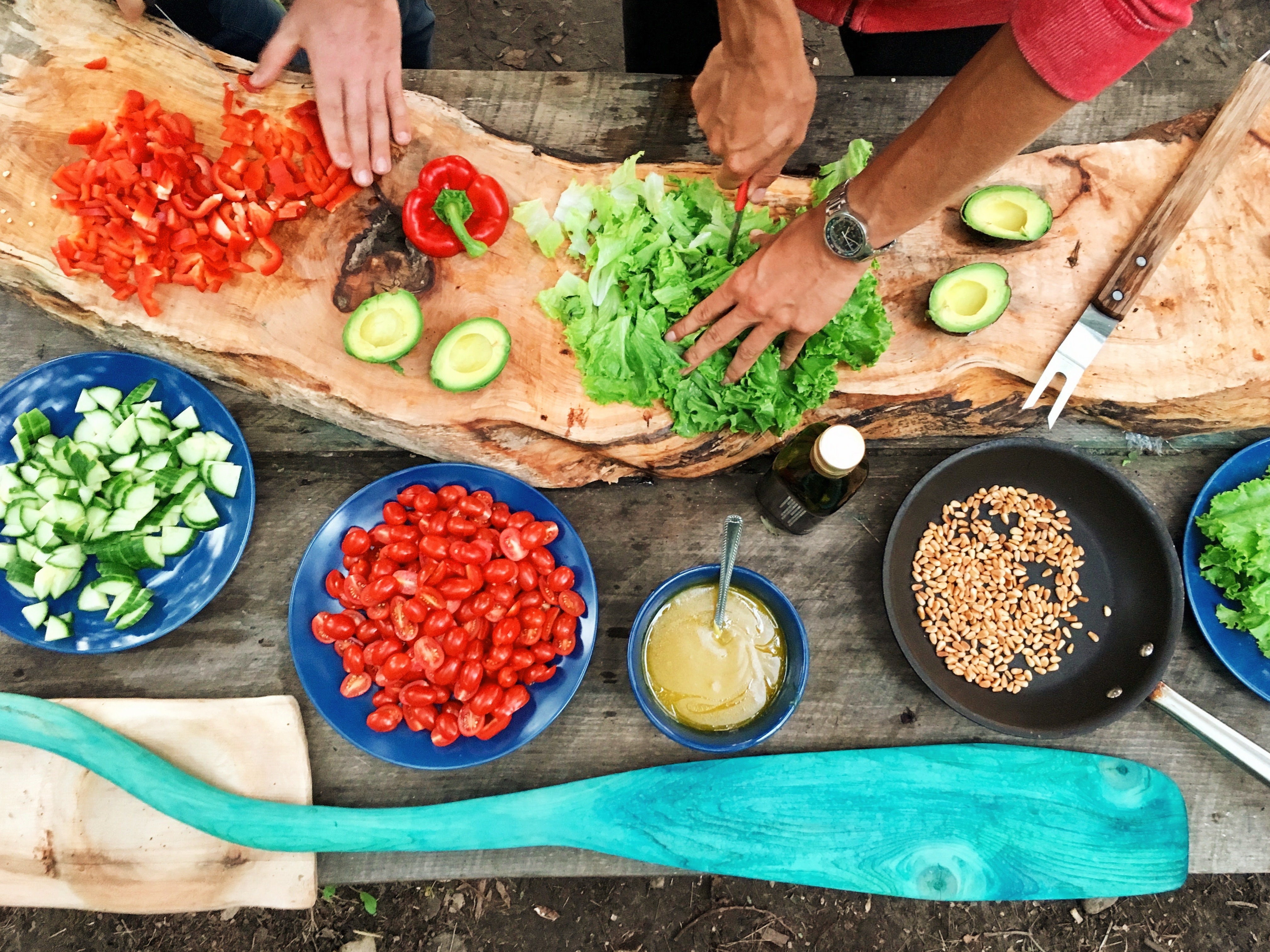 hands cutting lettuce surrounded by other veggies