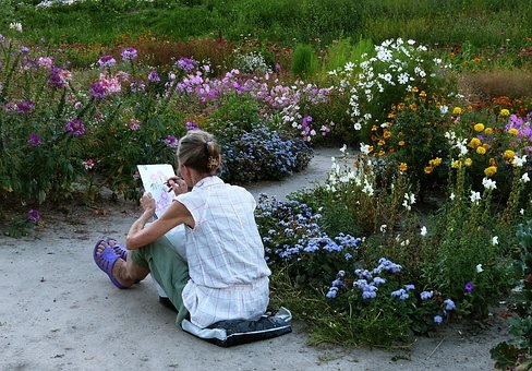 photo of a woman sitting on the ground in a journal sketching
