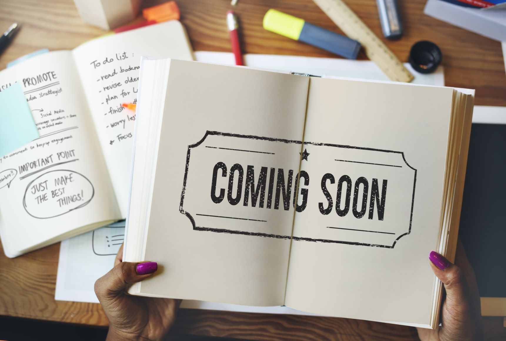 Picture of a book open, being held by two hand. Text in book says Coming Soon