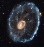 A galaxy with a small yellow center and blue spokes radiating out from it to a blue ring.