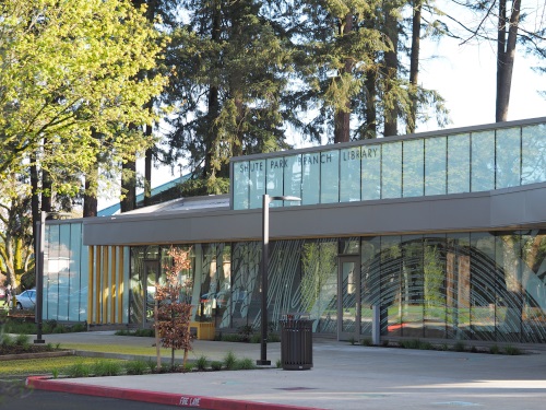 The front of the Shute Park branch, a glass-fronted building surrounded by trees.
