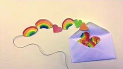 A string of paper rainbows and hearts lies half-out of an envelope.