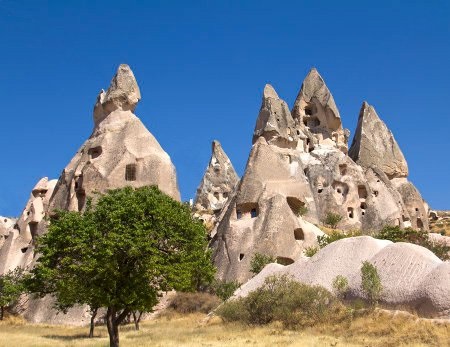 The windows of these homes peer out from their roughly conical rock formation exteriors.