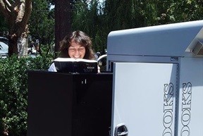 A grinning staff member reads a book from the book return.