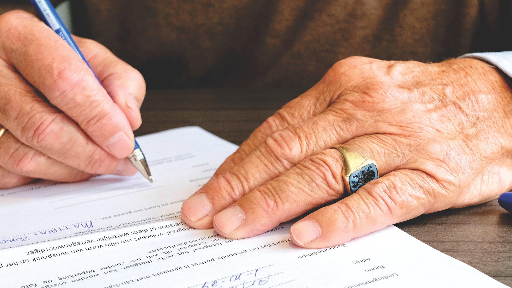 Senior Person Signing on Retirement Forms using Pen 