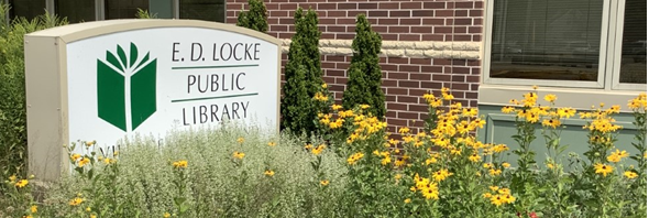 A picture of the E.D. Locke Public Library sign in a bed of blooming wildflowers.