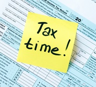 Picture of tax forms and a yellow post note with text "Tax time!"