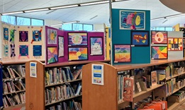 Picture of student artwork displayed on top of library shelves in children's area.