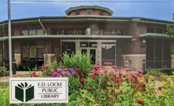 Picture of E.D. Locke Library card featuring flowers outside the exterior of the building and the library logo in the lower left corner.