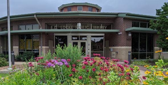 Picture of a the entrance to E.D. Locke Public Library with colorful flowers in the foreground.