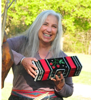 Picture of a woman with long gray hair smiling and holding a piece of Native art.