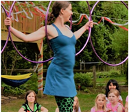 Picture of a woman performing with hula hoops in front of a group of children.