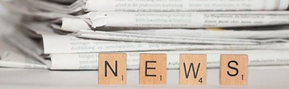 Newspaper in front of Scrabble letter pieces that spell out 'News'