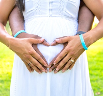 Two pairs of hands on a pregnant belly