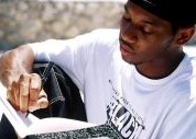 African-American teen boy wearing a white t-shirt and writing in a journal.