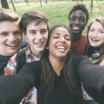 Group of smiling teens taking selfie.