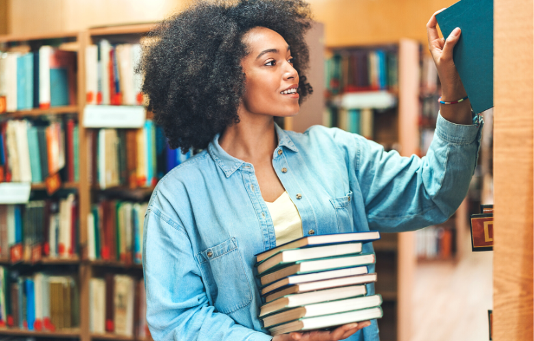 Woman holding stack of books in library