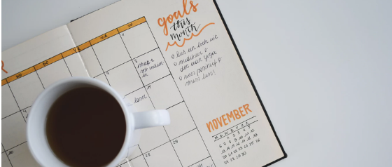 A picture of an open planner with a cup of coffee on top