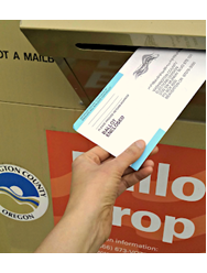 A hand places an election ballot in a ballot drop.