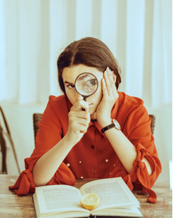 Picture of a teen with a magnifying glass and a book 