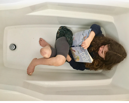 Photo of child reading in a bathtub