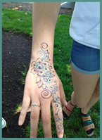 Person showing hand decorated with henna and glitter