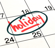 Closeup of a calendar with "holiday" written on the 25th.