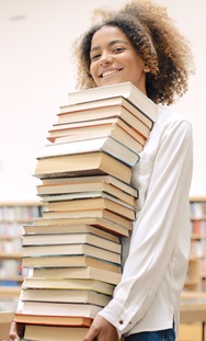 Person holding a very tall stack of books.