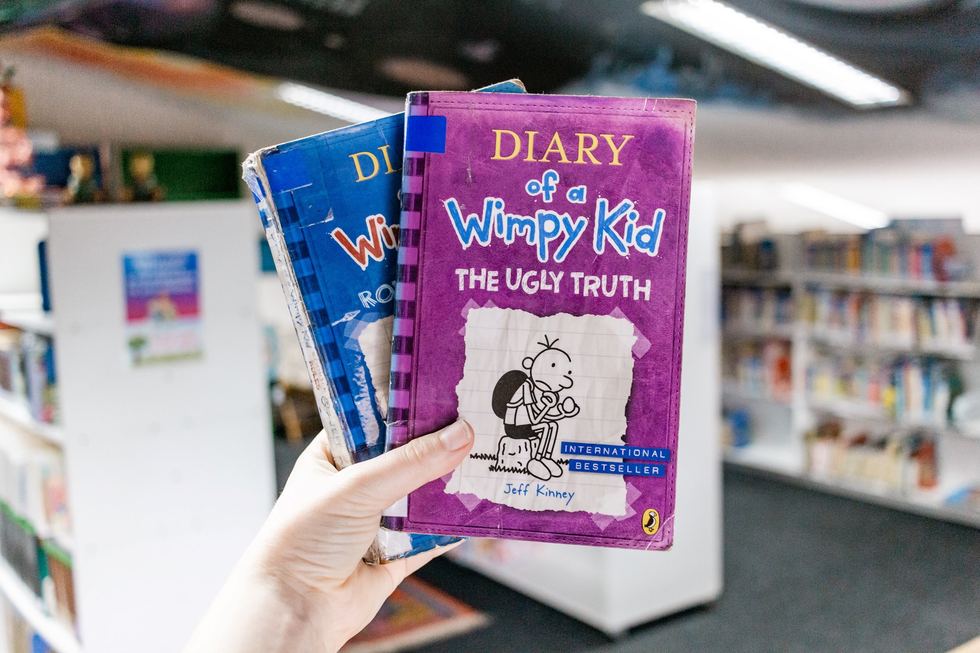 hands hold Diary of a Wimpy Kid books