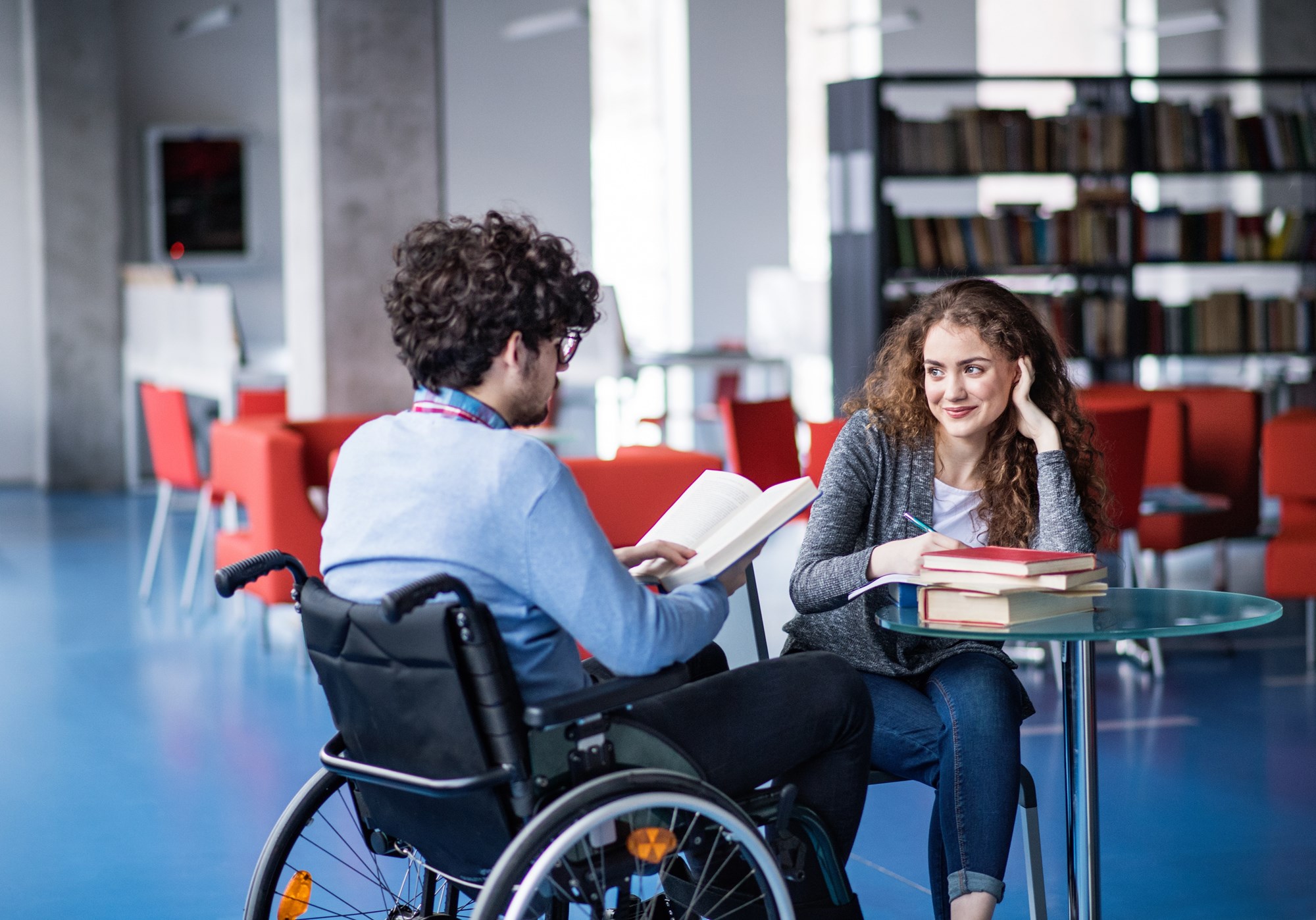 teen in a wheelchair reading with another teen at the library