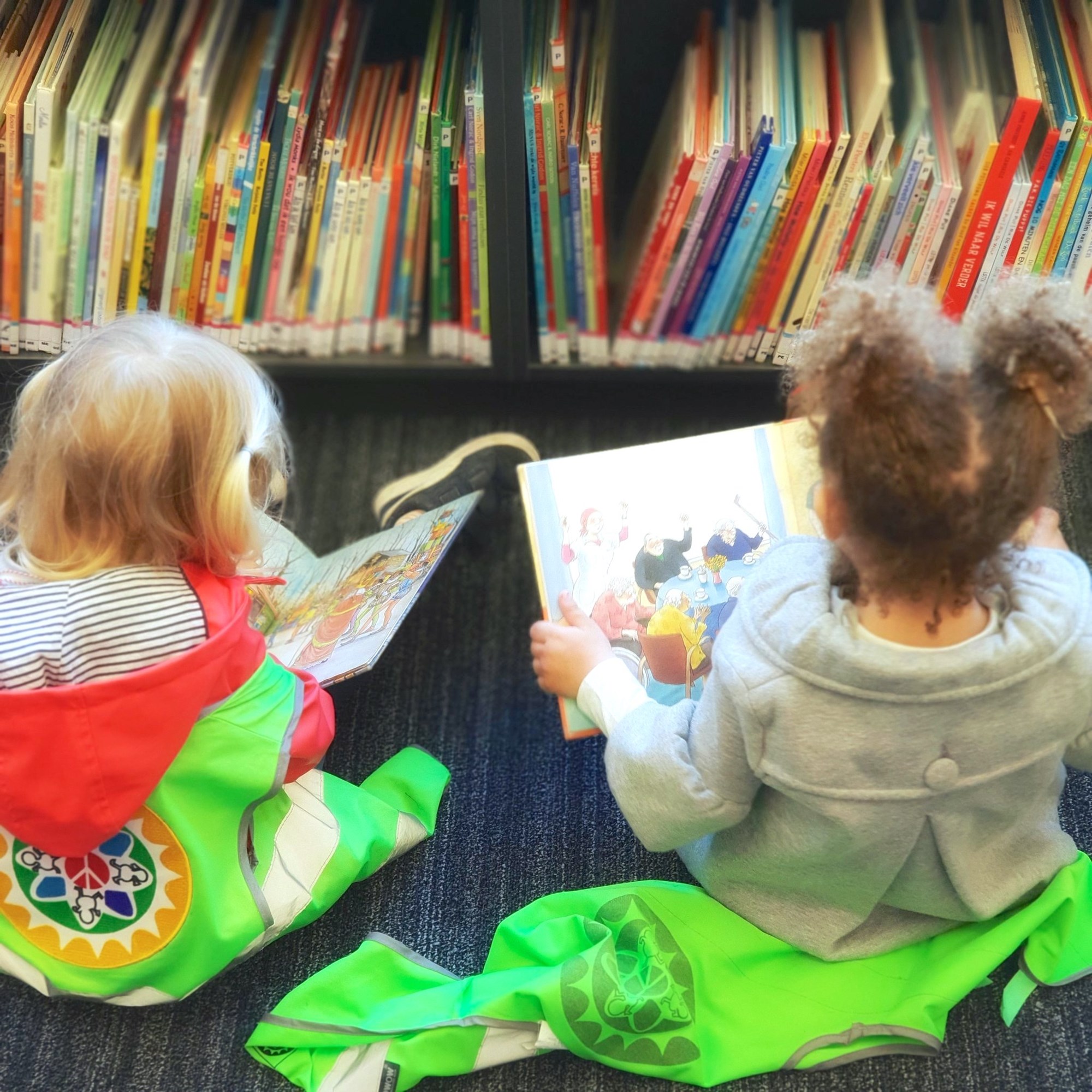 Two small children reading while sitting on library floor