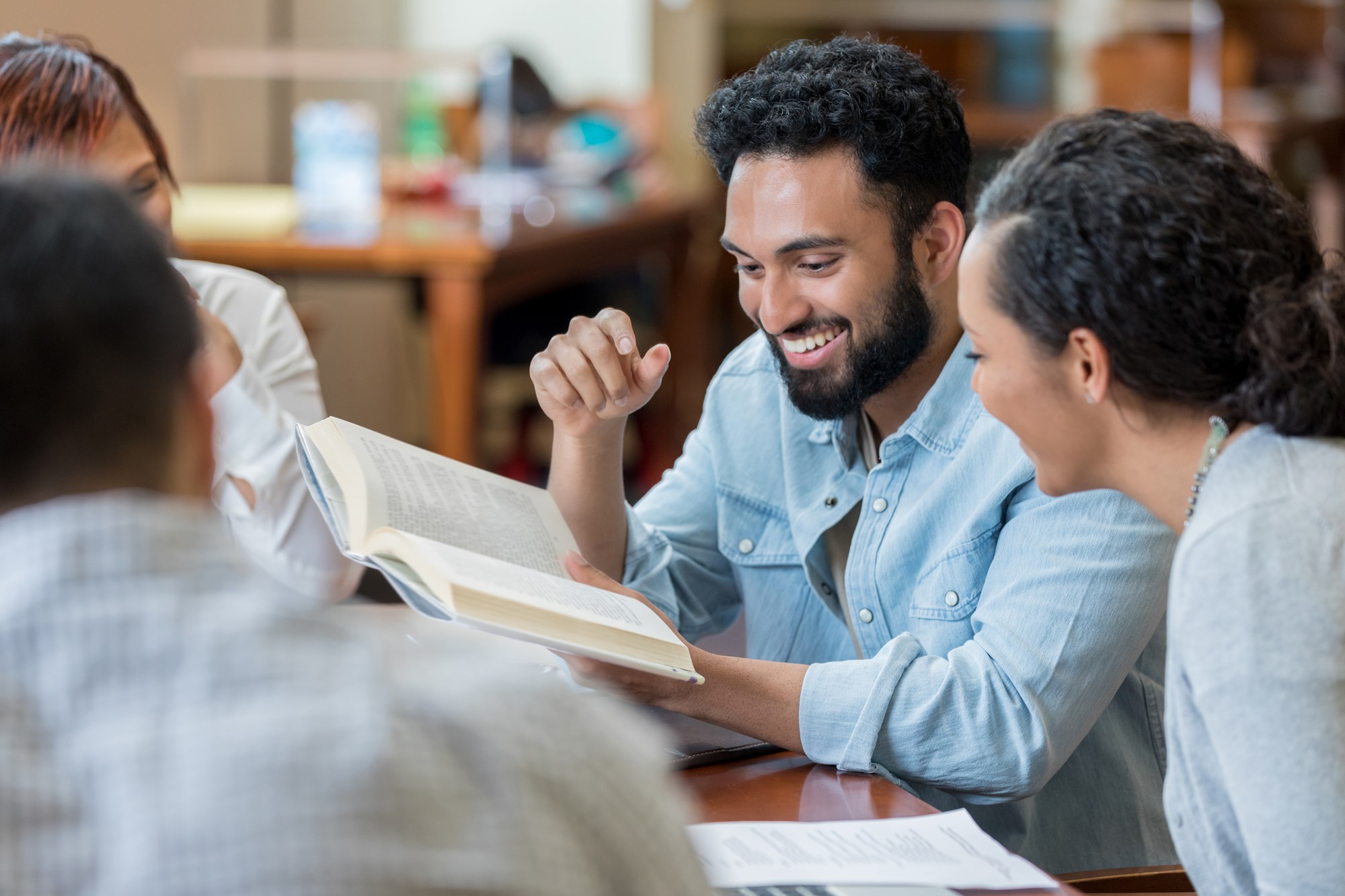 group of adults sitting discussing a book