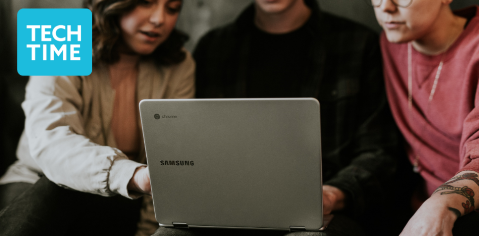 A photograph of three light-skinned people looking at a laptop screen.