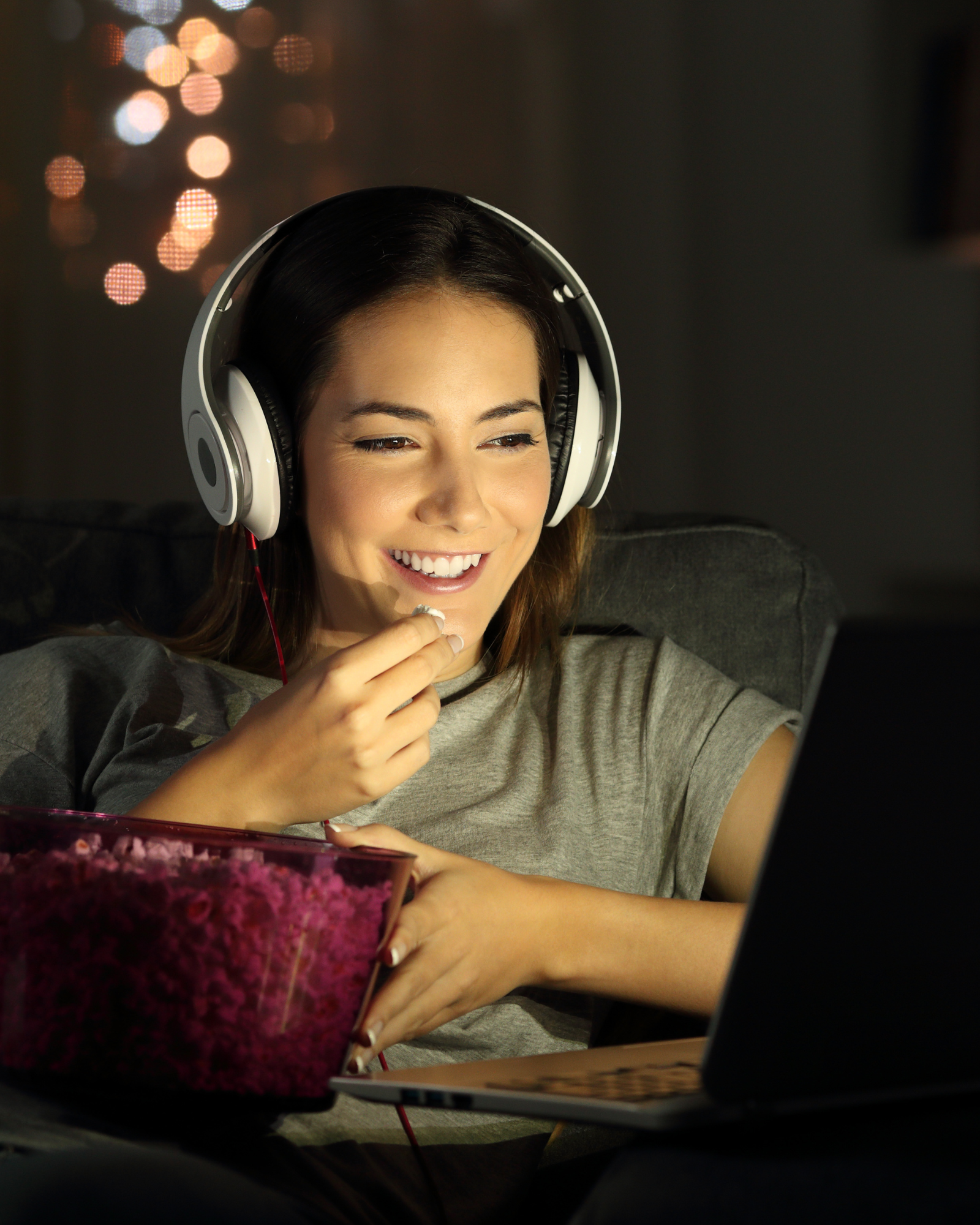 woman watching movie on laptop while eating popcorn