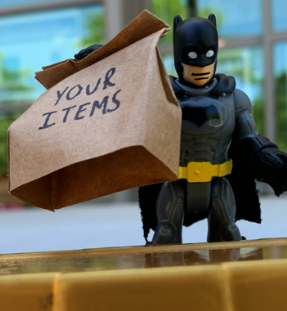 Toy batman holding a bag that says your items