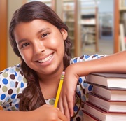 Smiling young girl with her arm on a stack of library books.