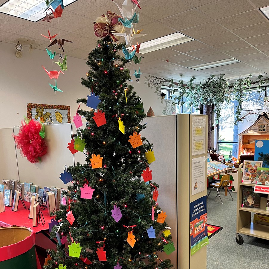 Photo of the Giving Tree decorated with colorful tags in the shape of gifts inside the library lobby.