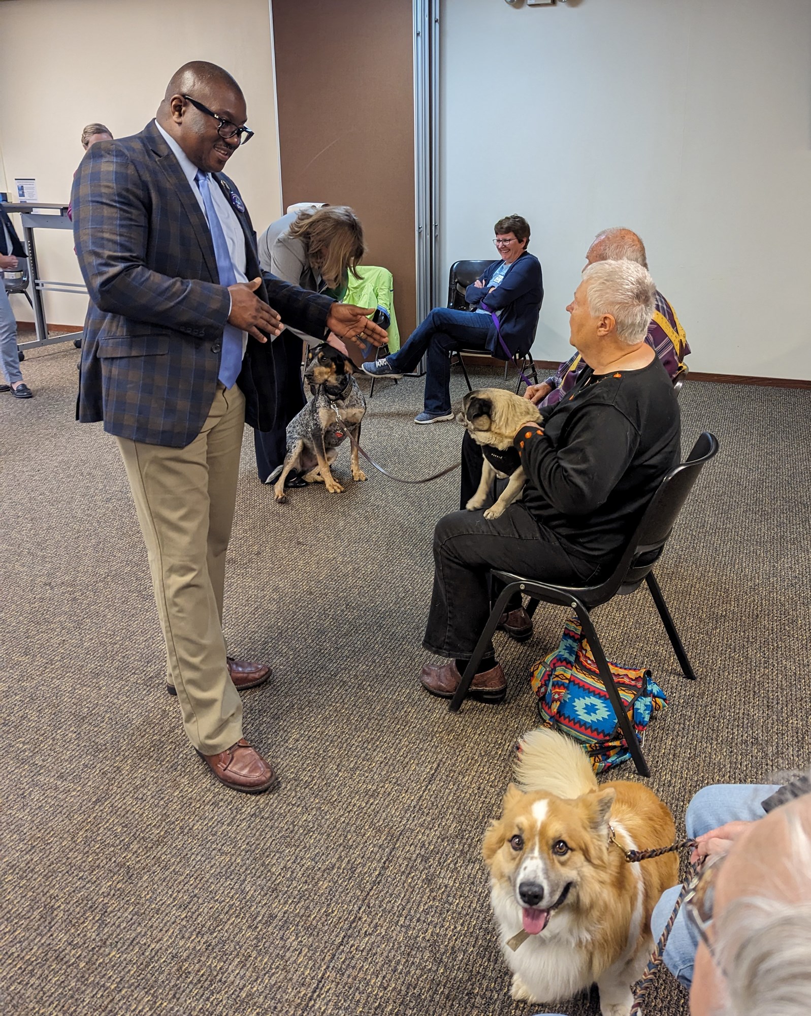 Photo of Dr. Darrell Williams standing and speaking to a woman sitting in a chair holding a pug dog.