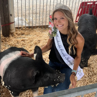 Photo of Jayden Rather, Waukesha County's "Fairest of the Fair" smiling at the camera with a hog.