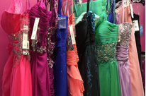 Photo of a rack of colorful prom dresses.