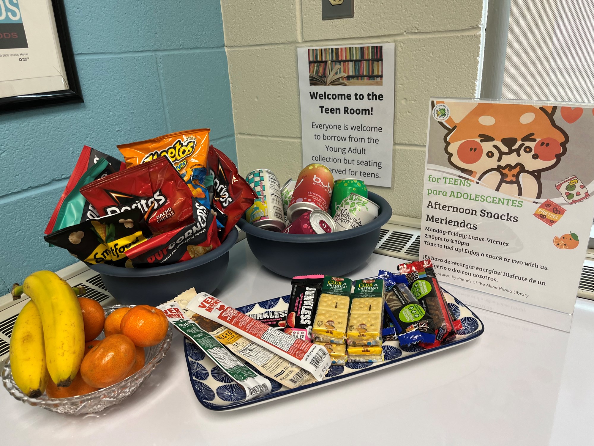 A photo of snacks available for teens in the Teen Room, including fruit, chips, drinks and other assorted snacks.
