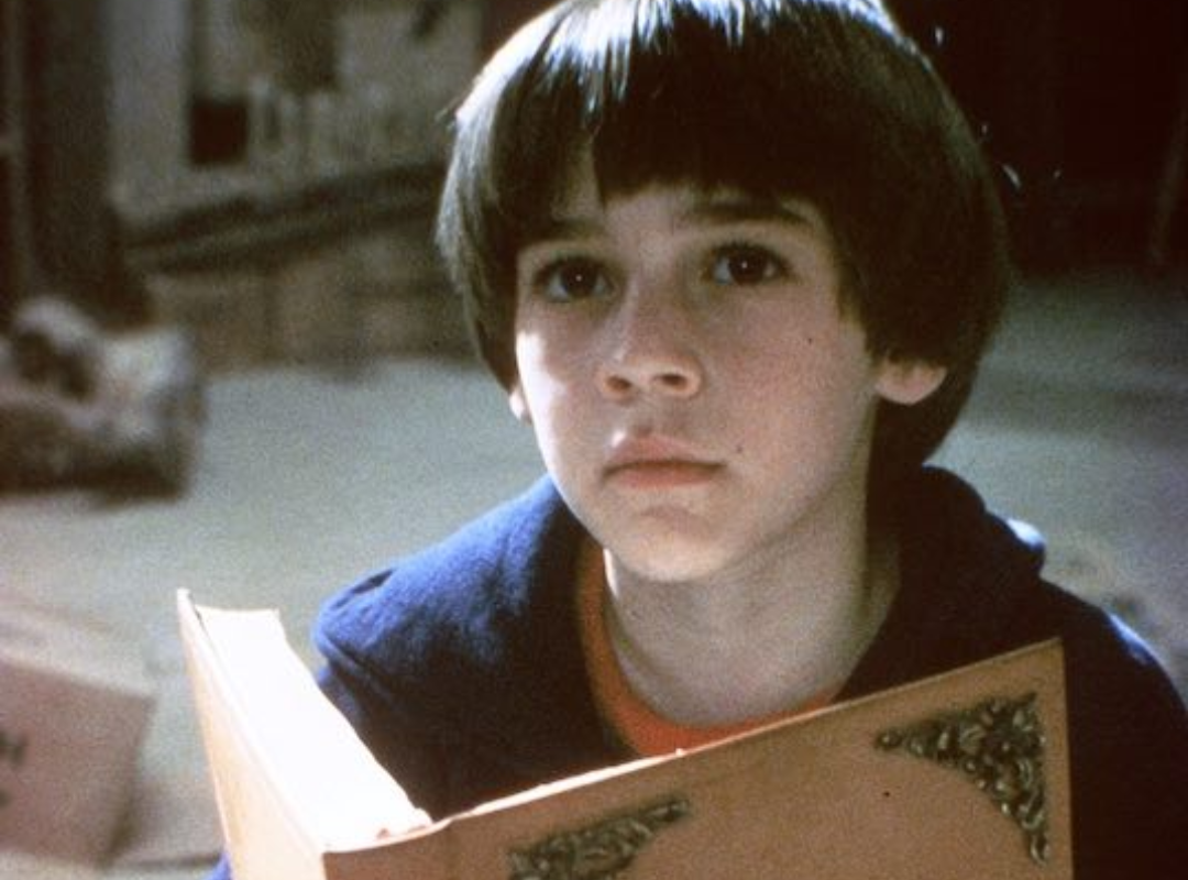 A screenshot from The NeverEnding Story, featuring protagonist Bastian holding a book.